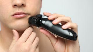 Mann rasiert sich mit Rasierer (Elektrorasierer)