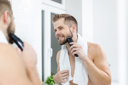 Mann rasiert sich das Gesicht mit einem Barttrimmer & Bartschneider